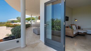 A modern room with a glass door, a sofa, and a view of the outdoors. - Villa Luna Del Sol l Unique Oceanview l Coral Estate Resort (Sint Willibrordus)