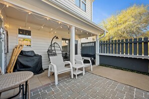 Une terrasse couverte, aménagée avec du mobilier d’extérieur, un barbecue et un panneau indiquant un restaurant de fruits de mer local.