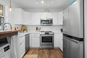 Une cuisine moderne avec des armoires blanches, des appareils en acier inoxydable et un plan de travail en bois.