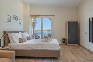 Ein Schlafzimmer mit Bett, Kleiderschrank, Sessel, kleinem Tisch und einem Fenster mit Blick.