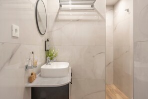 Een moderne badkamer met een wit wastafelmeubel, een spiegel en een douchehoek.
