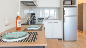 A modern kitchen with white cabinets, a stainless steel refrigerator, a microwave, and a coffee maker. - Studio 'Next To The Wave 2' with Sea View and Private Terrace (Μυρτιές)