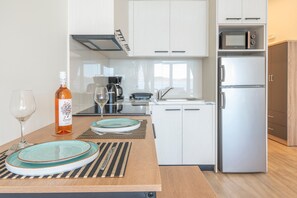 Eine moderne Küche mit weißen Schränken, einem Edelstahlkühlschrank, einer Mikrowelle und einer Kaffeemaschine.