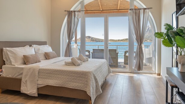 A bedroom with a large bed, a view of the sea, and a balcony with outdoor furniture. - Studio 'Next To The Wave 2' with Sea View and Private Terrace (Μυρτιές)