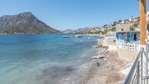 A coastal view with a rocky beach, a wooden pier, and a mountain in the background. - Studio 'Next To The Wave 2' with Sea View and Private Terrace (Μυρτιές)