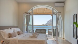 A bedroom with a large bed, a view of the sea, and a balcony with chairs. - Studio 'Next To The Wave 2' with Sea View and Private Terrace (Μυρτιές)