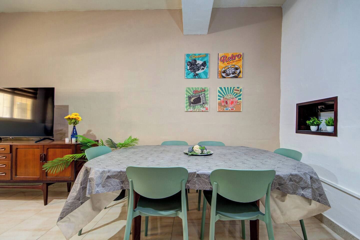 A dining area with a table, chairs, a TV, and wall decorations.