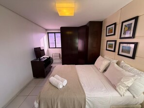 A hotel room with a bed, a TV, a dresser, and framed pictures on the wall. - Príncipe de Granada - Miramar (João Pessoa)