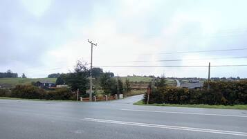 A rural road intersection with a traffic island, a pedestrian crossing, and a sign indicating a school zone.