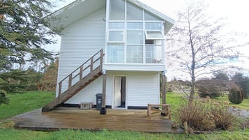 A two-story house with a wooden deck, a staircase, and a door leading to the interior.