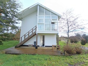 A two-story house with a wooden deck, a staircase, and a door leading to the interior.