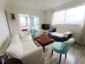 Una sala moderna con sofá, sillón, mesa de centro y televisor.