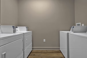 Una sala de lavandería con dos lavadoras, una secadora y un lavadero.