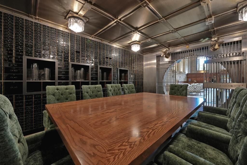 Un salón de conferencias con una larga mesa de madera y sillas tapizadas en verde.