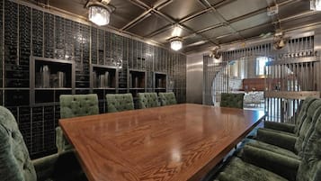Un salón de conferencias con una larga mesa de madera y sillas tapizadas en verde.