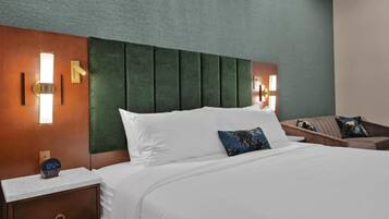 A hotel room with a large bed, a nightstand with a clock, and a wall-mounted light fixture.
