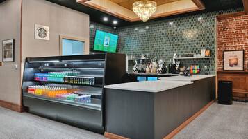 A modern bar area with a beverage display, a menu board, and a brick wall.