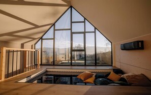A high-ceilinged room with a large window, a wooden floor, and a bed with pillows. - Flowfort View Private Hottub & Sauna Cottage Lekko (Stara Kamienica)