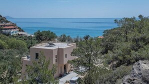 Ein Küstengebäude mit flachem Dach, umgeben von Bäumen und freiem Blick auf das Meer.