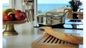 Eine Küche mit Meerblick, einer Obstschale, einem Brotlaib und einem Topf auf der Arbeitsfläche.