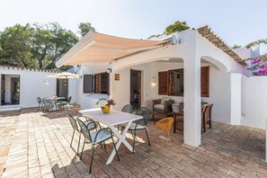 An outdoor patio with a table and chairs, a covered seating area, and a brick floor. - Casa Charlotte – 4 Bedroom Villa with Private Pool near Albufeira Beaches (Olhos de Água)