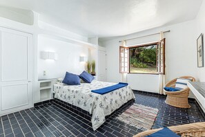 A bedroom with a bed, a window, a wicker chair, and a small table. - Casa Charlotte – 4 Bedroom Villa with Private Pool near Albufeira Beaches (Olhos de Água)