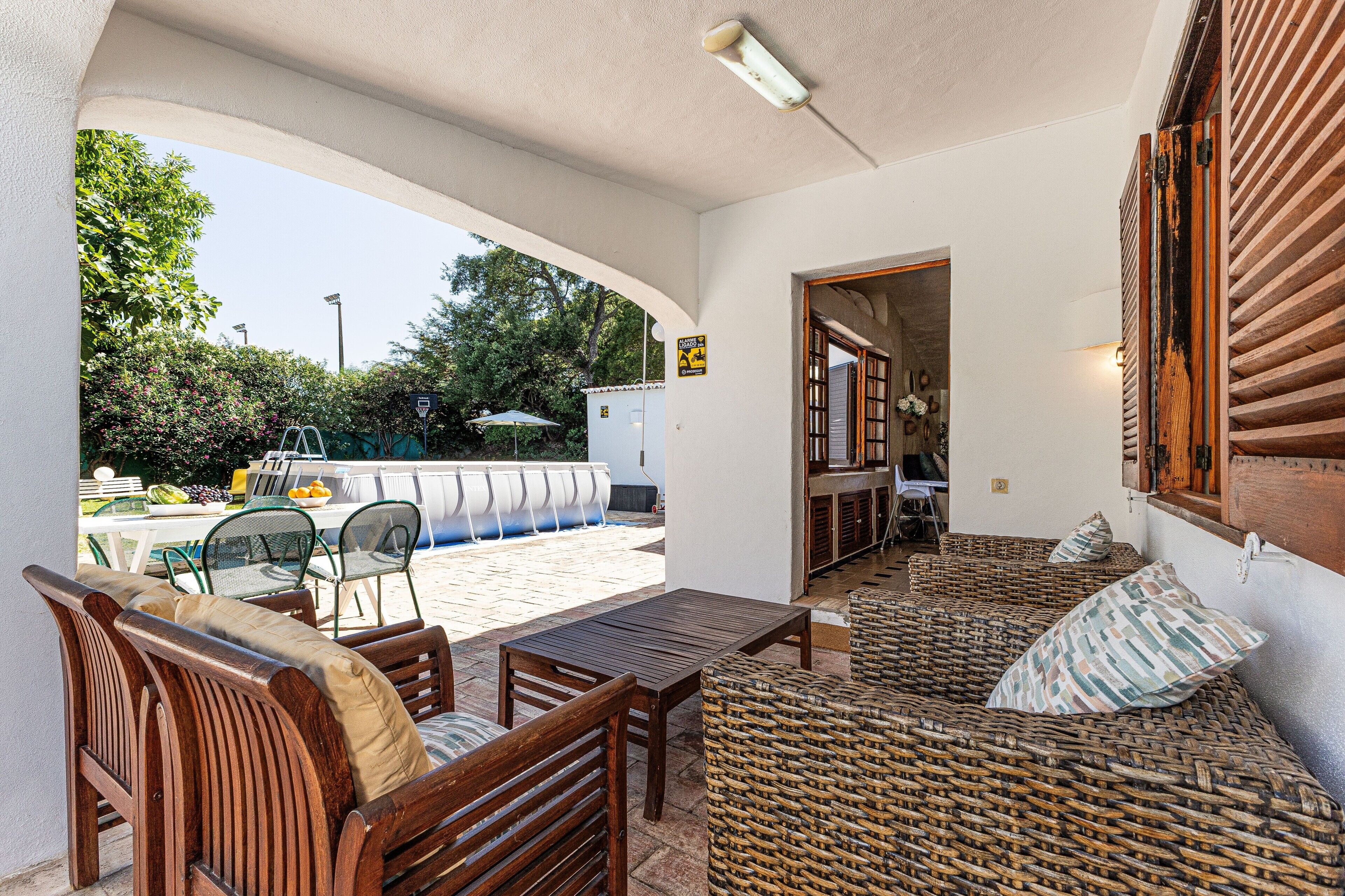 Eine Terrasse im Freien mit Holzmöbeln, einem Pool und einem überdachten Sitzbereich.