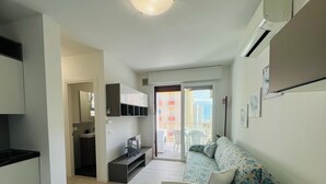 A modern apartment with a kitchenette, a sofa, a dining table, and a balcony with a view. - Bright Apartment 150m From the Beach (San Michele al Tagliamento)