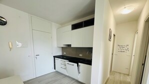 A modern kitchen with white cabinets, a black countertop, and a wooden floor. - Bright Apartment 150m From the Beach (San Michele al Tagliamento)