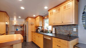 A modern kitchen with wooden cabinets, stainless steel appliances, and a tiled backsplash. - *New Listing* Breathtaking Views of Endless Ocean (Oceanside)