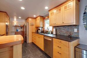 A modern kitchen with wooden cabinets, stainless steel appliances, and a tiled backsplash.