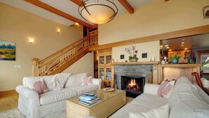 A living room with two white sofas, a coffee table, a fireplace, and a wooden staircase. - *New Listing* Breathtaking Views of Endless Ocean (Oceanside)
