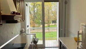 A modern kitchen with a large window, a dining area, and a view of a garden. - Spacious, light-filled apartment inside the ancient town walls, with great views (Treviso)