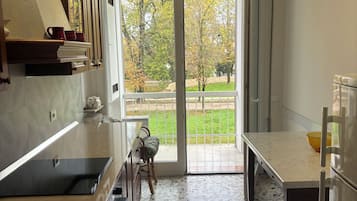 Una cucina moderna con una grande finestra, un'area pranzo e vista su un giardino.