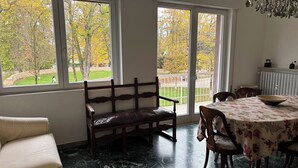 A room with a sofa, a bench, a dining table with chairs, and large windows with a view of trees and a lawn. - Spacious, light-filled apartment inside the ancient town walls, with great views (Treviso)