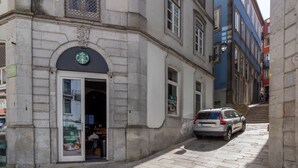 Un edificio con letrero de Starbucks, un coche aparcado y una escalera que lleva a otro edificio.