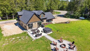 A house with a patio, outdoor seating, and a fire pit. - Cabin w/ hot tub near Cana Island Lighthouse (Baileys Harbor)