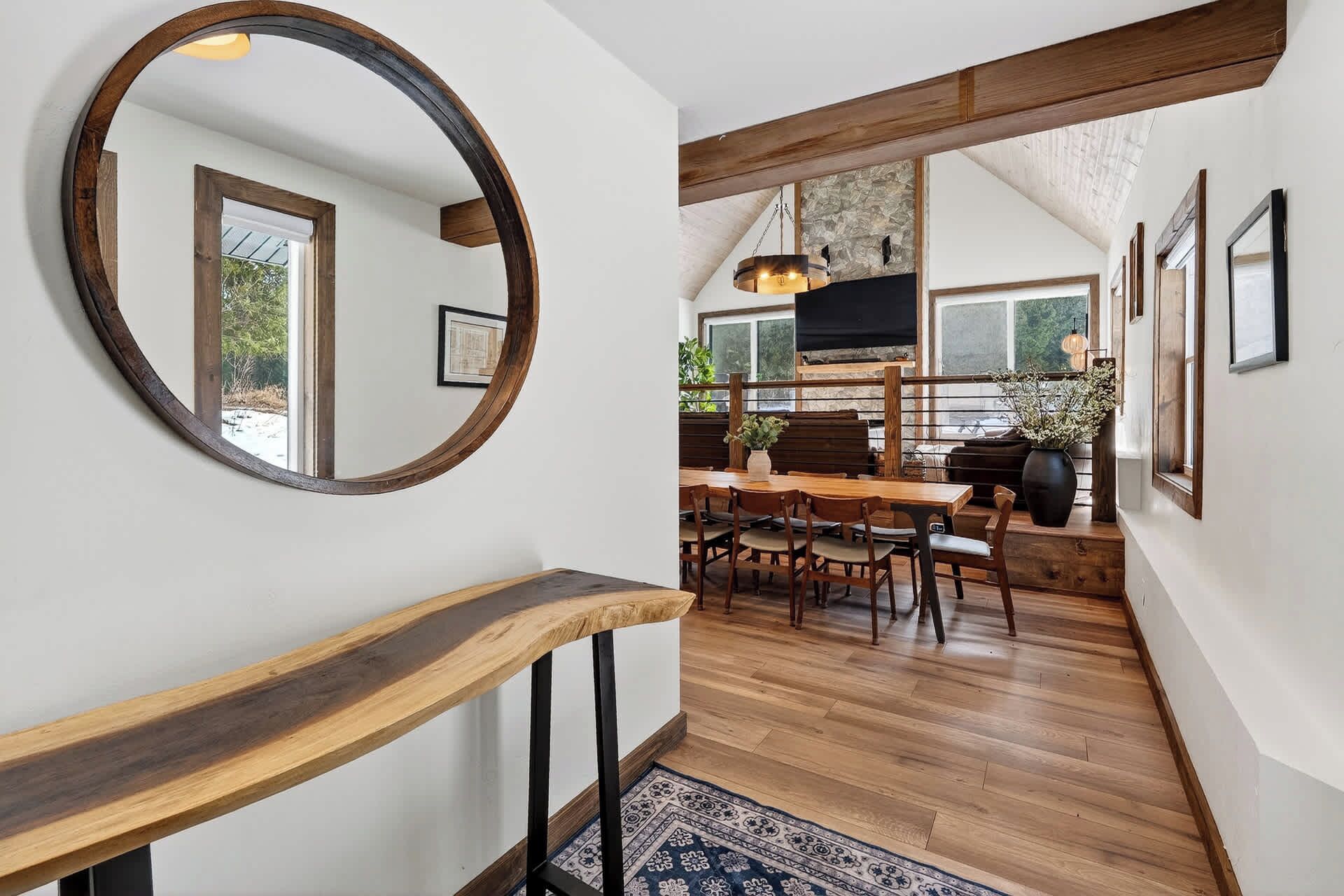 A wooden staircase leading to a dining area with a large mirror, wooden beams, and a stone wall.