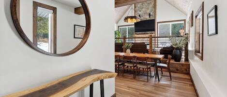 A wooden staircase leading to a dining area with a large mirror, wooden beams, and a stone wall.