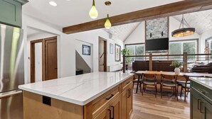 A kitchen with a marble countertop, wooden cabinets, and a dining area with a table and chairs. - Cabin w/ hot tub near Cana Island Lighthouse (Baileys Harbor)