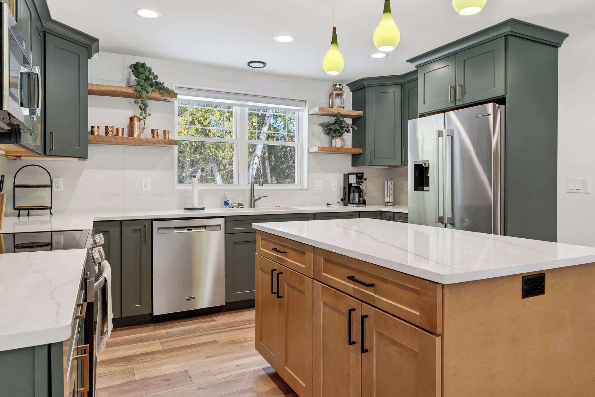 A modern kitchen with a central island, built-in appliances, and pendant lighting.