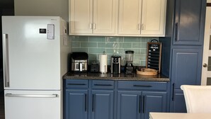 Een keuken met een koelkast, koffiezetapparaat, broodrooster, blender en een menubord.