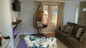 Een woonkamer met een bank, een fauteuil, een open haard en een televisietoestel.
