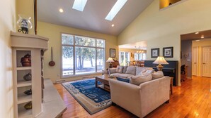 A spacious living room with a fireplace, a sofa, a coffee table, and a large window.