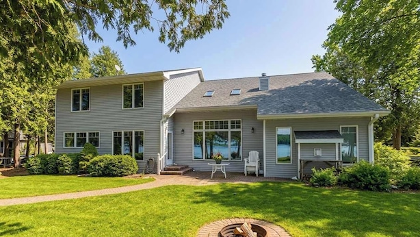 A two-story house with a fire pit in the front yard, a covered patio, and a small deck.