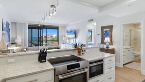 Een moderne keuken met een groot eiland, roestvrijstalen apparatuur en uitzicht op de oceaan.