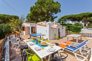 An outdoor patio with a dining table, chairs, and lounge chairs.