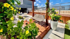 A rooftop terrace with wooden flooring, outdoor seating, and potted plants. - Compact Time - Miramar Hospedagens  (João Pessoa)