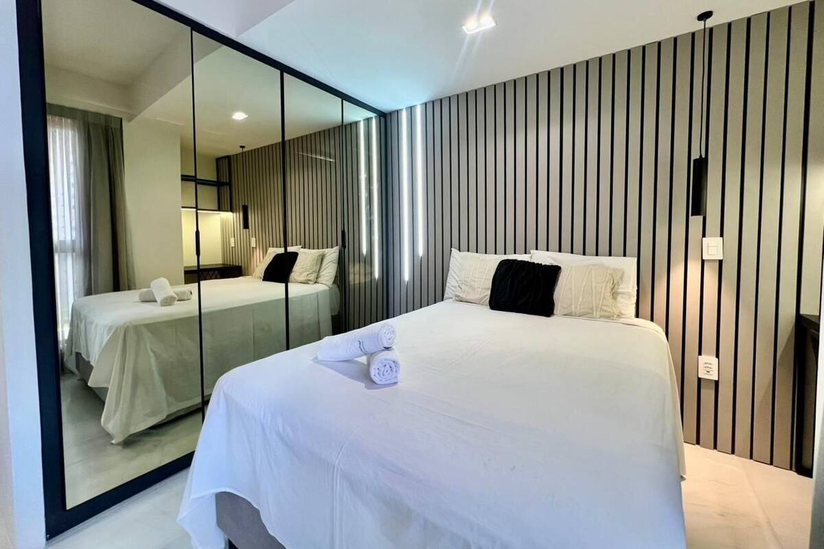 Una habitación de hotel moderna con una cama grande, un espejo y una pared a rayas.