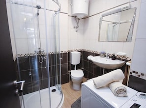A bathroom with a glass-enclosed shower, a toilet, a sink, and a washing machine. - Delux Konavle Village Apartment (Konavle)